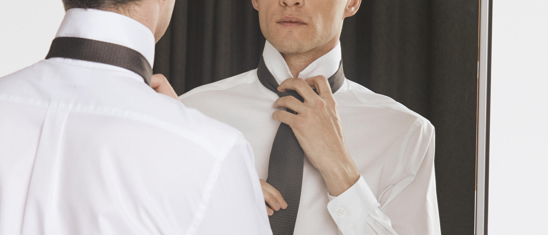 Mand i hvid Lindbergh skjorte som binder et sort Lindbergh slips